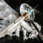 Drug syringe and cooked heroin on spoon