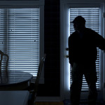 Burglar Breaking In To Home At Night Through Back Door