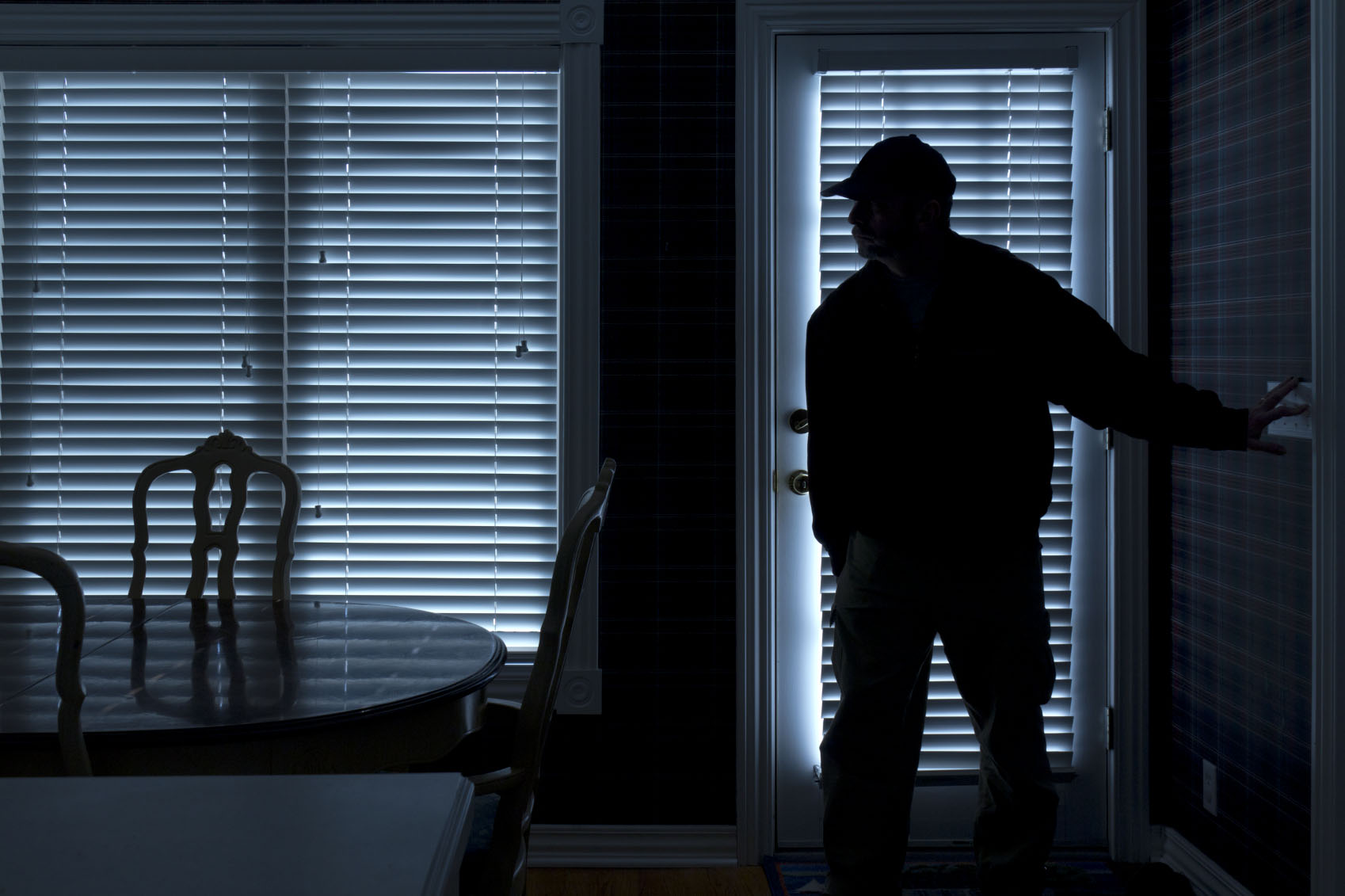 Burglar Breaking In To Home At Night Through Back Door