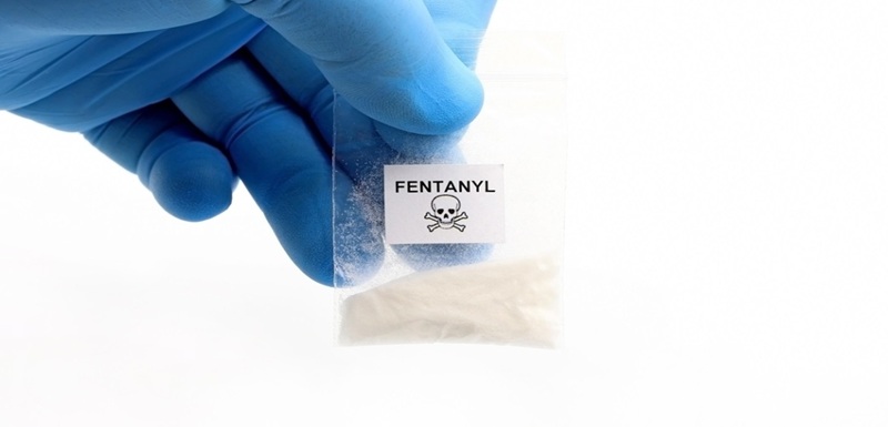 Blue glove holding a pouch of fentanyl, a potent opioid that causes overdose deaths